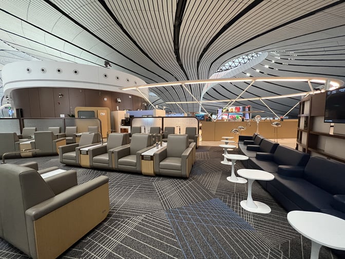 The seating area in China Southern Lounge at Beijing Daxing International Airport features individual chairs and couches with side tables.