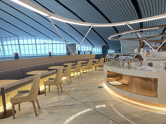 The China Southern Lounge at Beijing Daxing International Airport features a buffet area with chafing dishes and adjacent seating for dining.