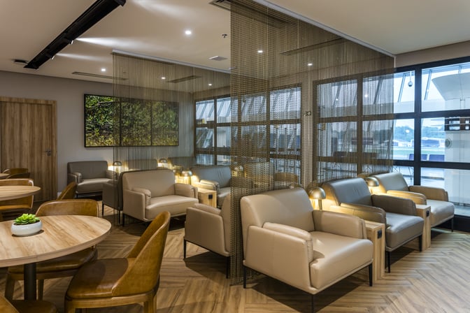 The seating area in W Lounge Belém features comfortable chairs and tables, providing a relaxing space for travelers at Val de Cans Airport.