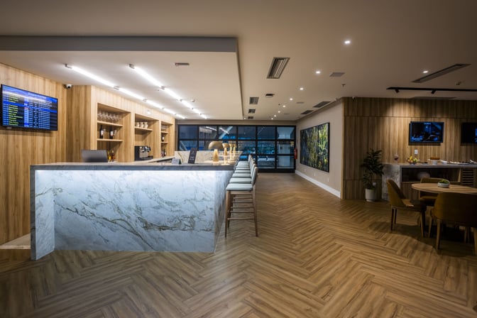 The W Lounge Belém features a bar area with high stools and a departure information screen, offering beverages and seating.