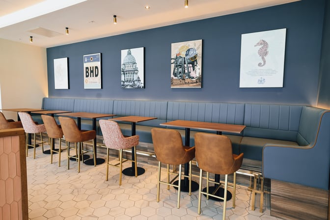 Booth seating in the Aspire Lounge at Belfast City Airport offers comfortable dining spaces with wall art depicting local landmarks.