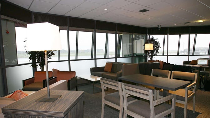 Seating area in the Causeway Lounge at Belfast International Airport features tables, chairs, and sofas with views of the tarmac.