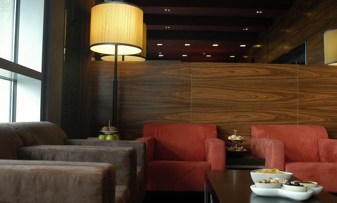 Seating area in Dan Lounge at Ben Gurion Airport features comfortable armchairs and a table with snacks for travelers.