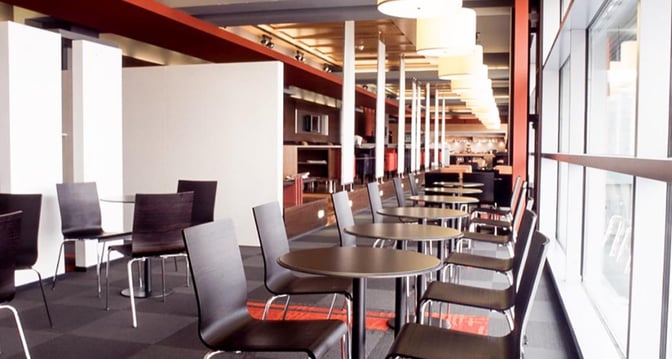 The seating area in Dan Lounge at Ben Gurion Airport features rows of tables and chairs with views of the tarmac.