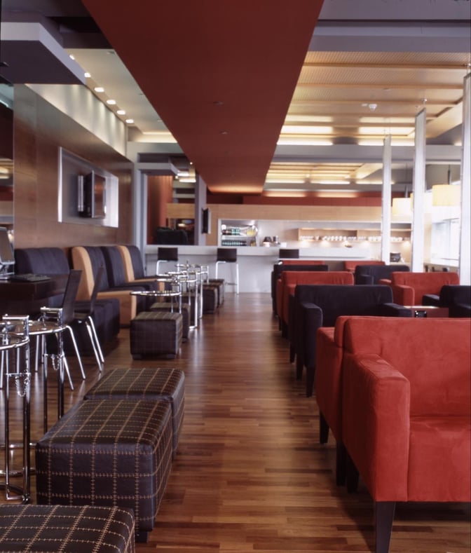 The Dan Lounge at Ben Gurion Airport features comfortable seating with tables and a self-serve beverage area in the background.