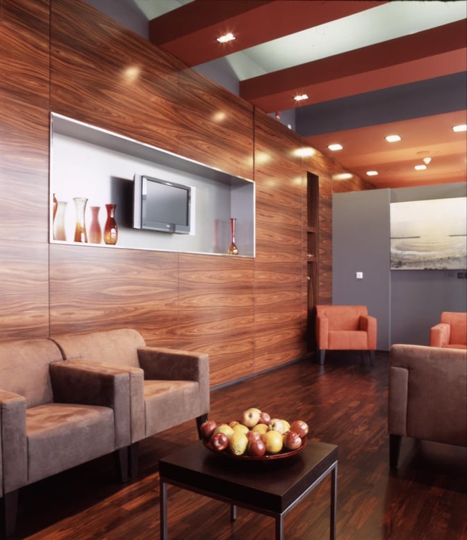 The seating area in Dan Lounge at Ben Gurion Airport features comfortable chairs, a wall-mounted TV, and a table with fruit.