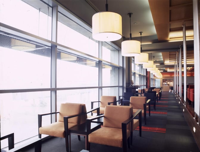 The seating area in Dan Lounge at Ben Gurion Airport features armchairs and tables along large windows with airport views.