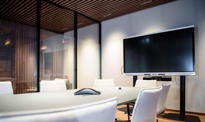 The conference room at Lounge Tegel in Berlin Brandenburg Airport features a large screen and seating for meetings or presentations.