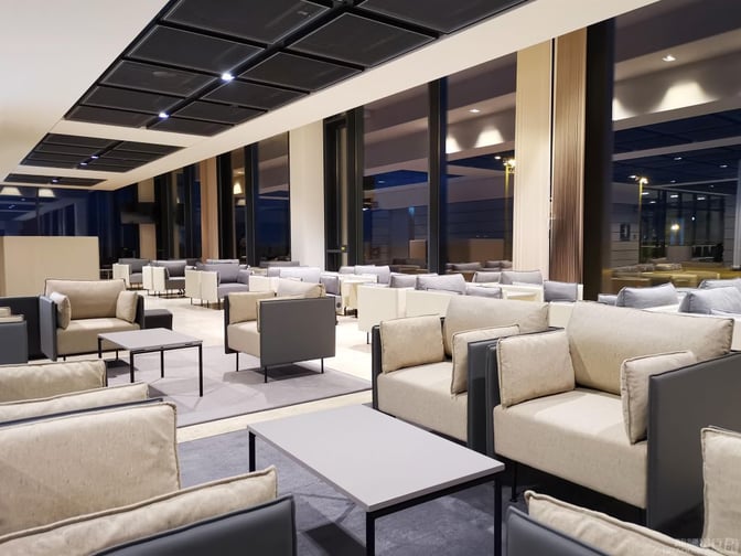The seating area in Lounge Tempelhof at Berlin Brandenburg International Airport features armchairs and tables arranged for passenger comfort.