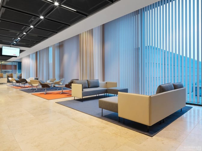 The Lounge Tempelhof at Berlin Brandenburg International Airport features spacious seating areas with armchairs and sofas, offering views of the tarmac.