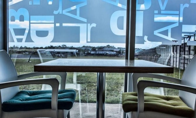 The seating area in Bidvest Premier Lounge at East London Airport offers table seating with views of the airport runway.