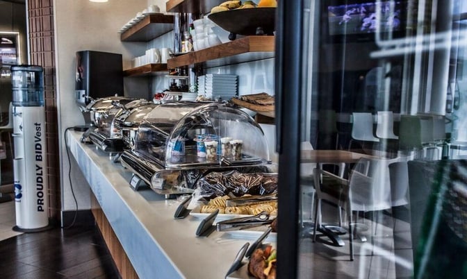 Self-serve buffet area at Bidvest Premier Lounge, East London Airport, offers a variety of covered dishes and snacks for travelers.