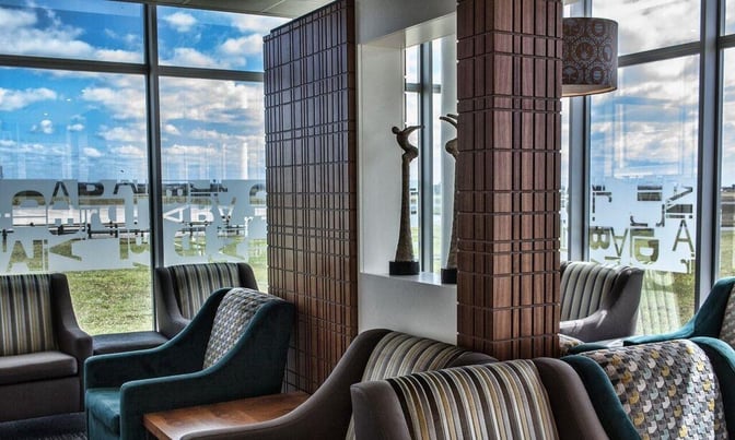Seating area in Bidvest Premier Lounge at East London Airport features comfortable chairs and decorative partitions with large windows offering outdoor views.