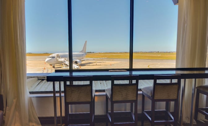The seating area in the Bidvest Premier Lounge at George Airport offers counter seating with views of the runway and parked aircraft.