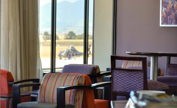Seating area in the Bidvest Premier Lounge at George Airport offers armchairs and tables with views of the airport runway.