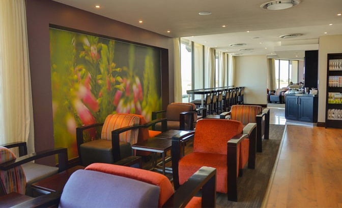 The Bidvest Premier Lounge at George Airport features comfortable seating with tables, a long counter area, and a snack station.