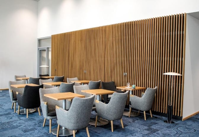 The seating area in King Amlet Lounge at Billund Airport features tables and chairs arranged for dining or relaxation.