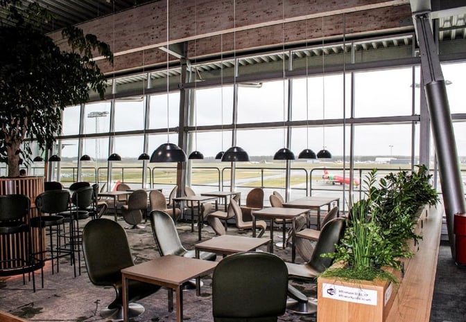 The seating area in King Amlet Lounge at Billund Airport offers tables and chairs with views of the airport runway.