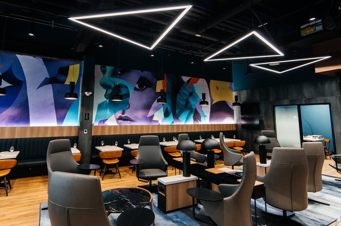 The Aspire Air Canada Cafe at Billy Bishop Toronto City Airport features a seating area with tables, chairs, and artistic wall decor.