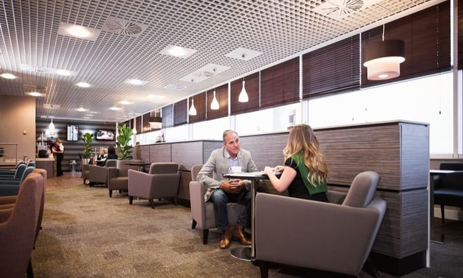 The Aspire Lounge North at Birmingham Airport features comfortable seating areas with tables, providing a relaxed space for travelers.