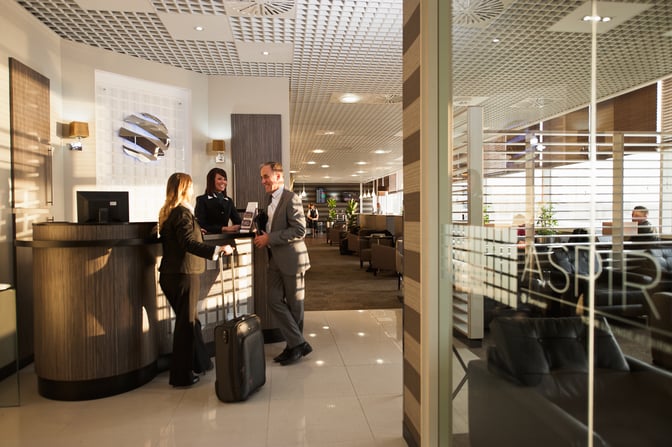 The reception area of Aspire Lounge North at Birmingham Airport features a check-in desk and seating visible in the background.