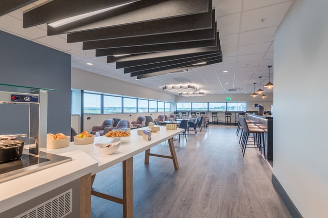 The Aspire Lounge South at Birmingham Airport features a self-serve food area with seating options and views of the runway.