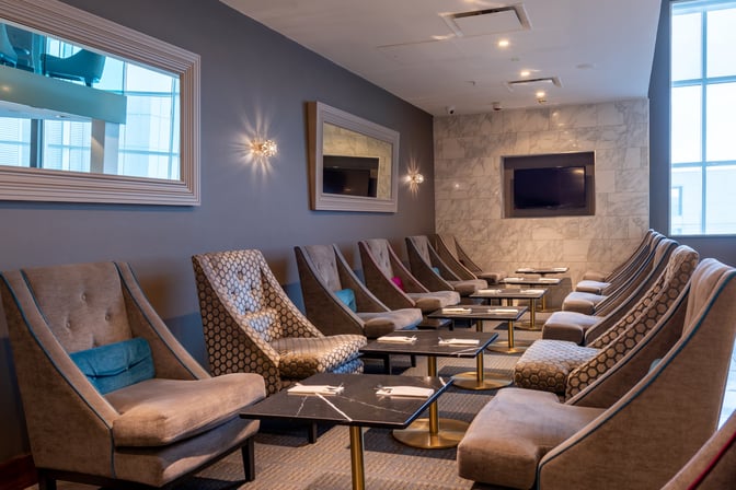 The seating area at No1 Lounge Birmingham Airport features comfortable chairs and tables arranged for relaxation and socializing.