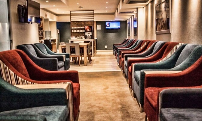 The seating area in the Bidvest Premier Lounge at Bram Fischer International Airport features armchairs and a self-serve refreshment station.