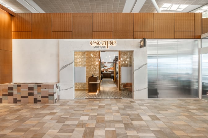 The Escape Lounge entrance at Brisbane Airport features a welcoming reception area with decorative wall panels and visible seating inside.
