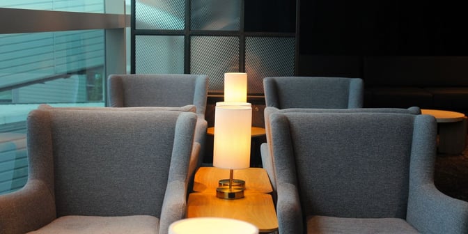 The seating area in Plaza Premium Lounge at Brisbane Airport features comfortable armchairs and small tables with lamps for relaxation.