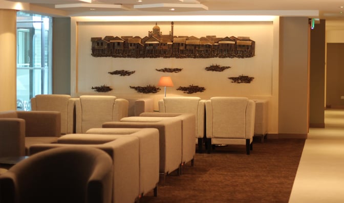 Seating area in Royal Brunei's Sky Lounge at Brunei International Airport features comfortable armchairs and a decorative wall installation.