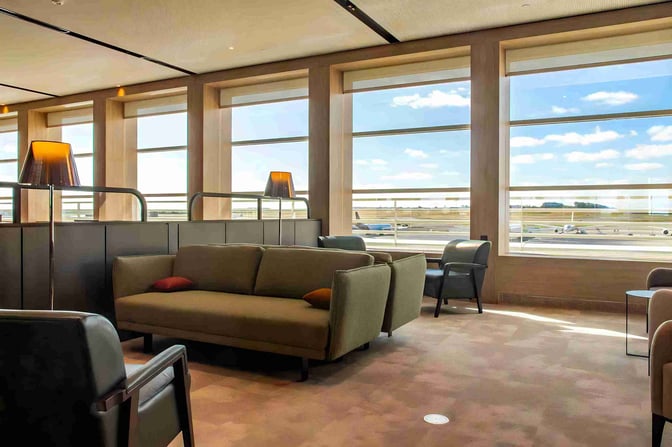 The seating area at The View lounge in Brussels Airport offers comfortable sofas and chairs with expansive views of the runway.