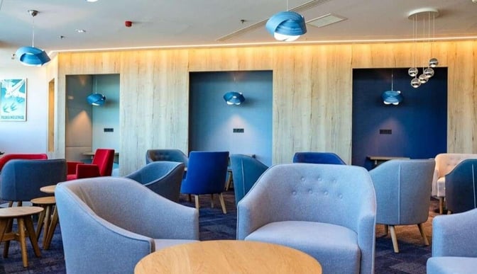 The seating area in Plaza Premium Lounge at Budapest Airport features comfortable chairs and small tables for relaxation and work.