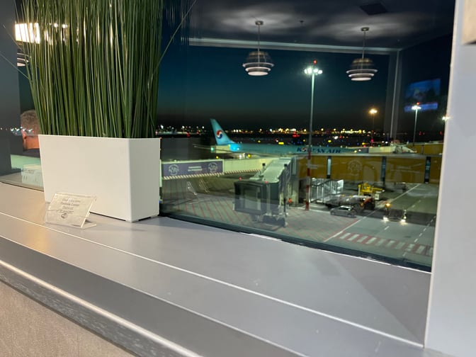 The Platinum Lounge at Budapest Airport offers views of the tarmac and parked aircraft through large windows, with seating nearby.