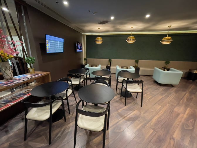 The Platinum Lounge at Budapest Ferenc Liszt International Airport features seating with tables and a flight information display screen.