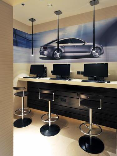 The SkyCourt Lounge at Budapest Airport features a computer station with three monitors and barstool seating for travelers.