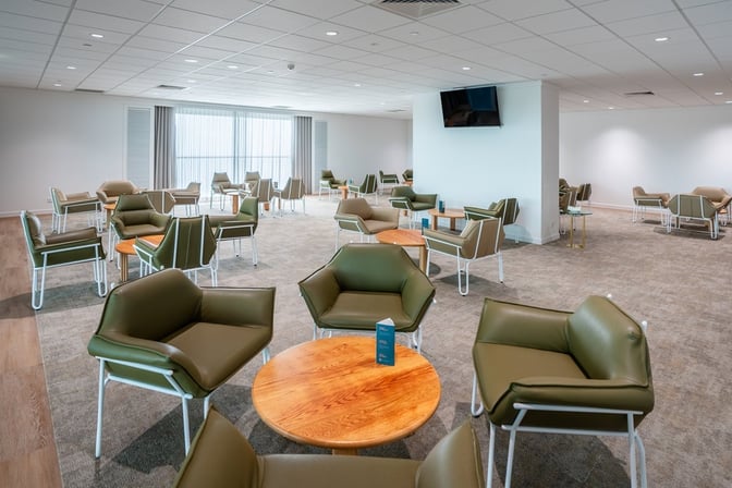 The seating area in Cairns Airport's Escape Lounge features comfortable chairs and round tables, providing a relaxing space for travelers.
