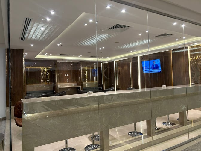 The CAC Lounge at Cairo International Airport Terminal 3E features a bar area with high stools and a television for guest entertainment.