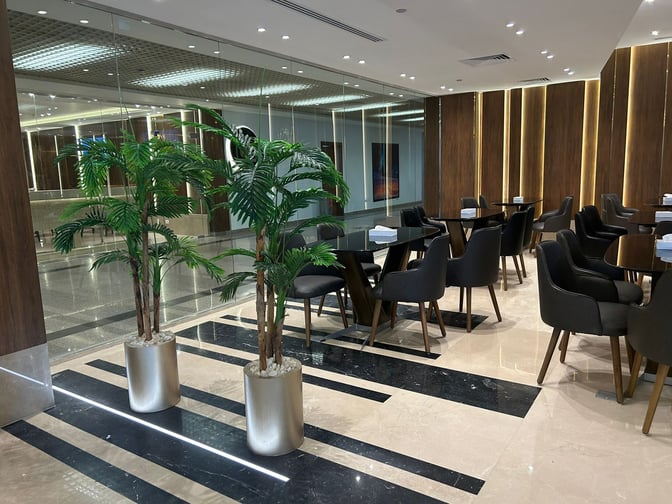 The seating area in the CAC Lounge at Cairo International Airport Terminal 3E features tables and chairs for dining or relaxation.