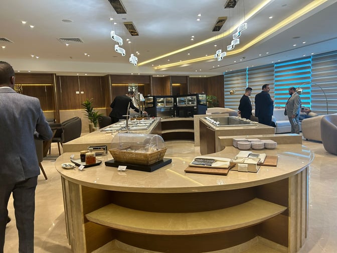 The CAC Lounge at Cairo International Airport Terminal 3E features a self-serve food area with various dining options and seating arrangements.