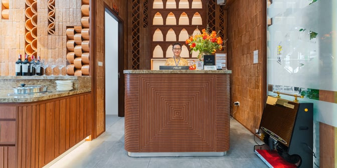 The reception area of SH Premium Lounge at Cam Ranh International Airport features a check-in desk with a staff member and decorative elements.