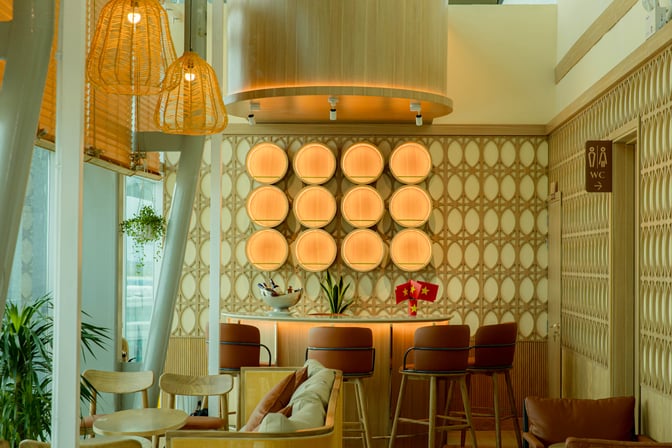 The SH Premium Lounge at Cam Ranh International Airport features a bar area with high stools and decorative wall elements.