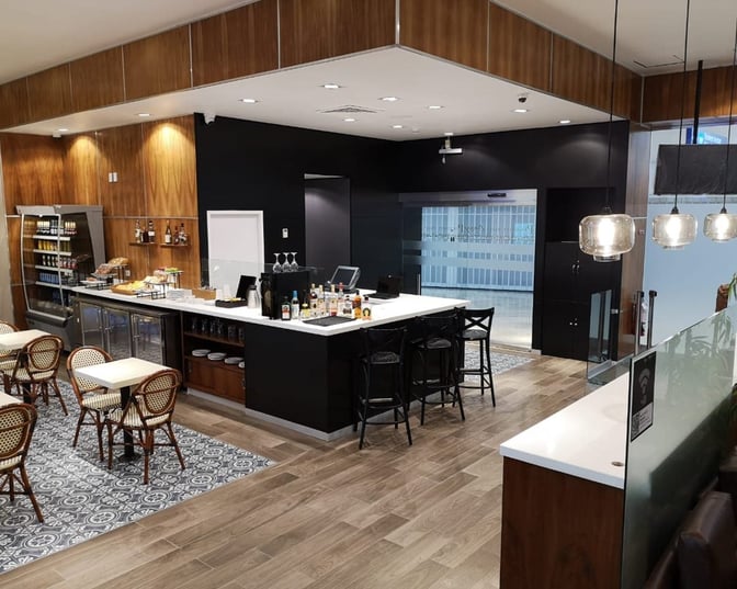 The MERA Business Lounge in Terminal 2 at Cancun International Airport features a bar with seating and a self-serve snack area.