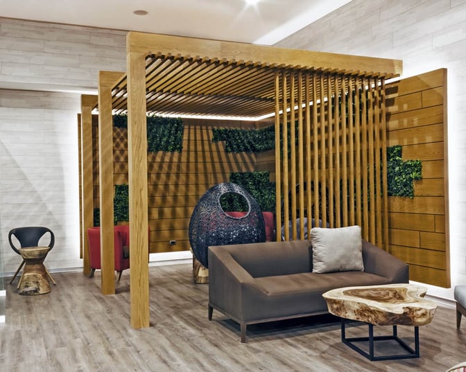 The seating area in MERA Business Lounge at Cancun International Airport features comfortable sofas and unique chairs with decorative wooden partitions.