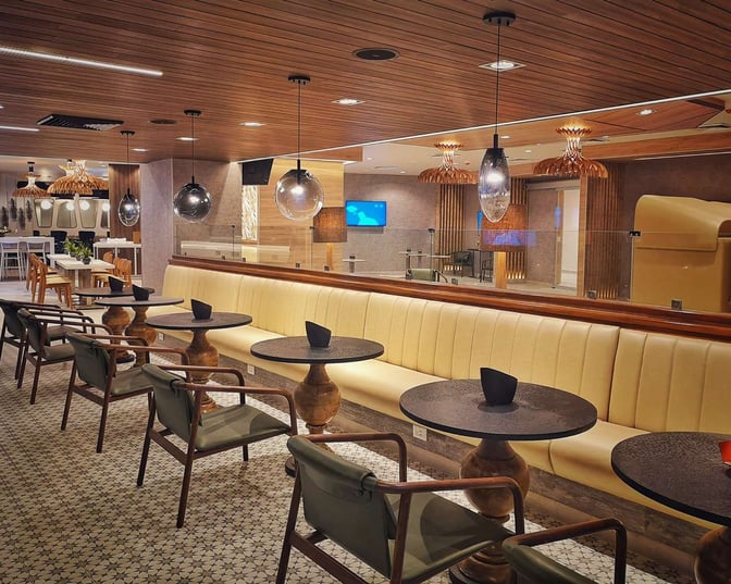 Seating area in MERA Business Lounge Terminal 4 Cancun Airport features booth seating with individual tables and overhead lighting.