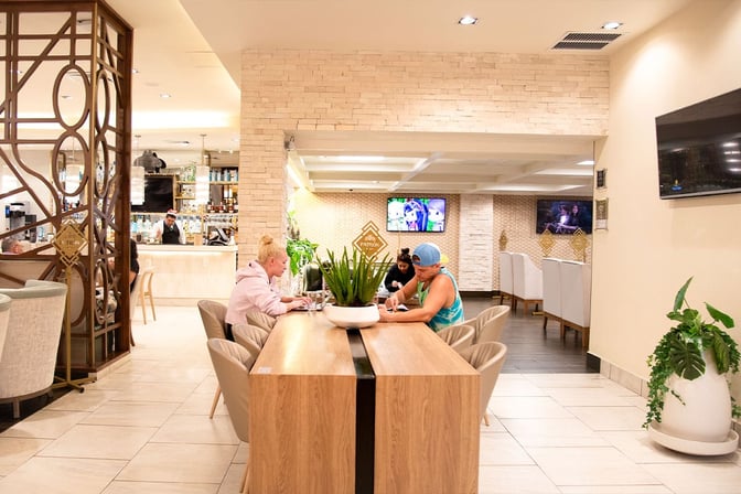 The MERA Business Lounge in Terminal 4 at Cancun International Airport features a bar area and communal seating with televisions.