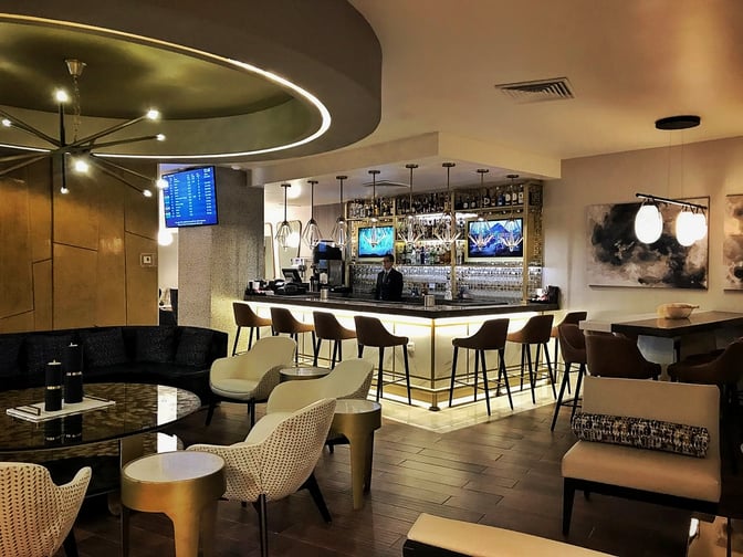 The MERA Business Lounge at Cancun International Airport features a bar with counter seating and a variety of spirits displayed.