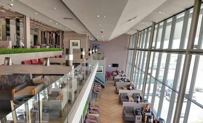 The Bidvest Premier Lounge at Cape Town International Airport features multi-level seating with airport views, offering comfortable chairs and tables for travelers.