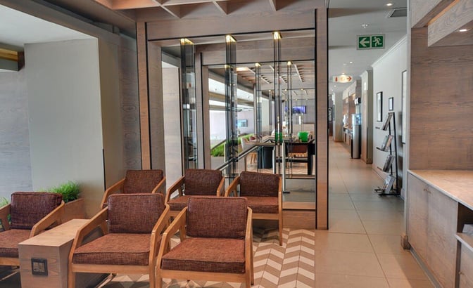Seating area in the Bidvest Premier Lounge at Cape Town International Airport features armchairs and a view into the main lounge area.