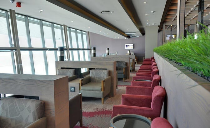 The Bidvest Premier Lounge at Cape Town International Airport features a seating area with armchairs and tables overlooking the tarmac.